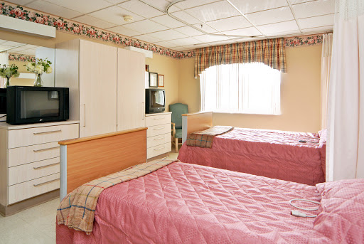 A cozy hotel room featuring two beds and a window with natural light.