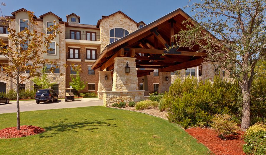 A modern residential building with a stone facade and well-maintained landscaping.