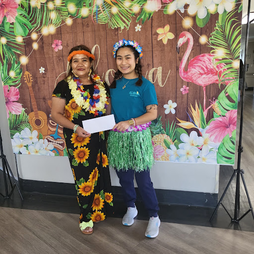 Two women dressed in festive attire pose together against a vibrant floral backdrop.