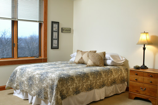 A cozy bedroom featuring a neatly made bed and natural light coming through the window.