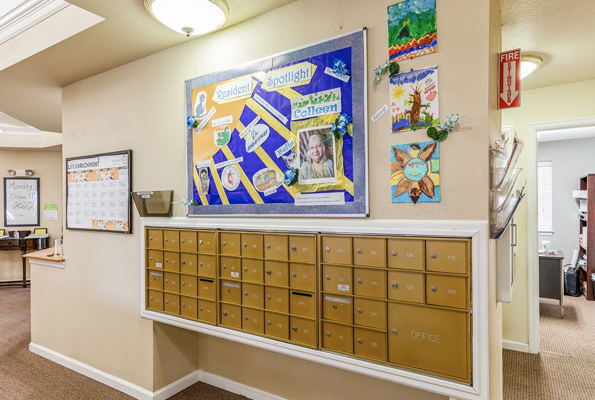 A hallway with multiple mailboxes and a colorful bulletin board on the wall.