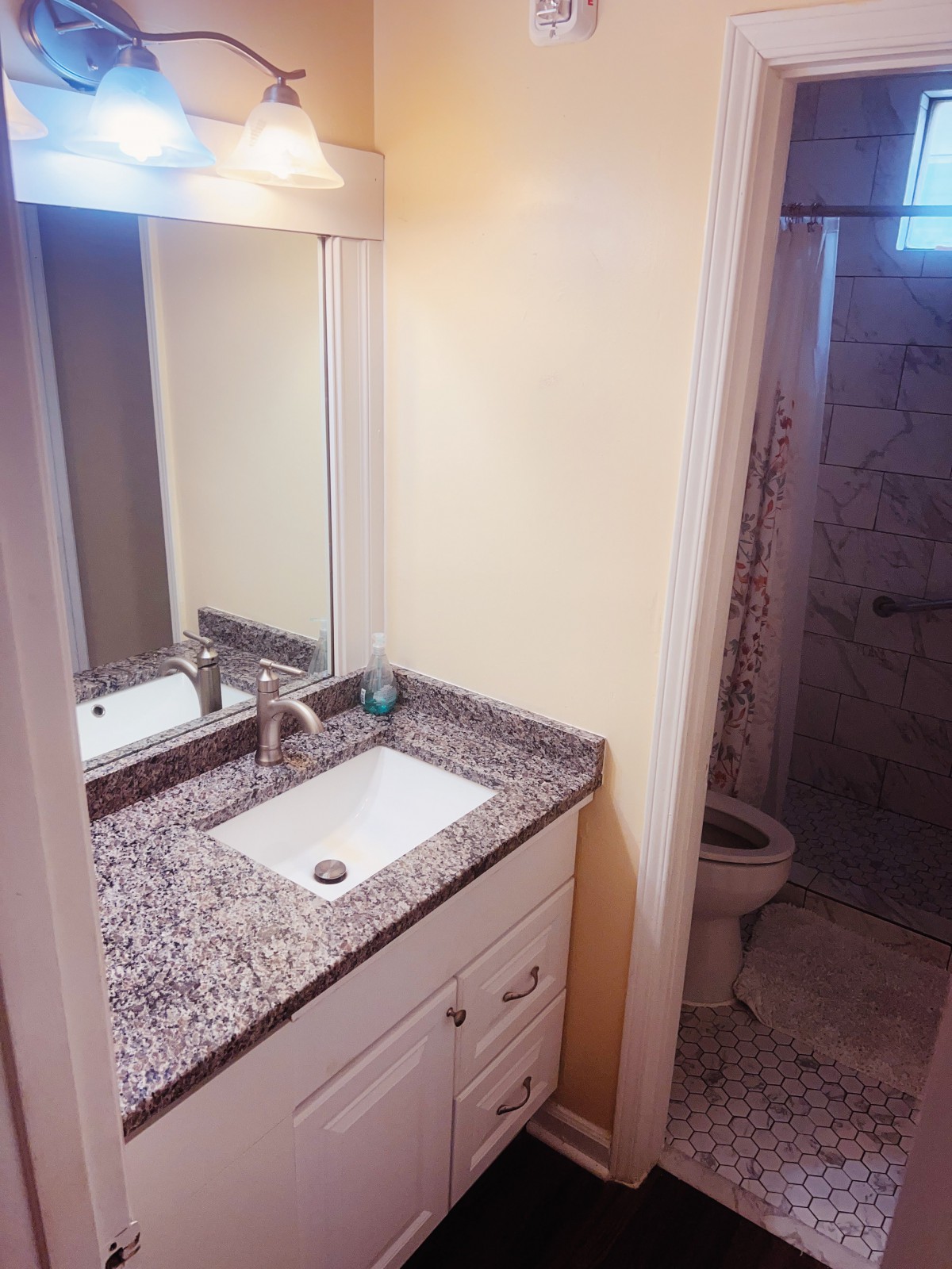 A modern bathroom with a granite countertop sink and a shower.