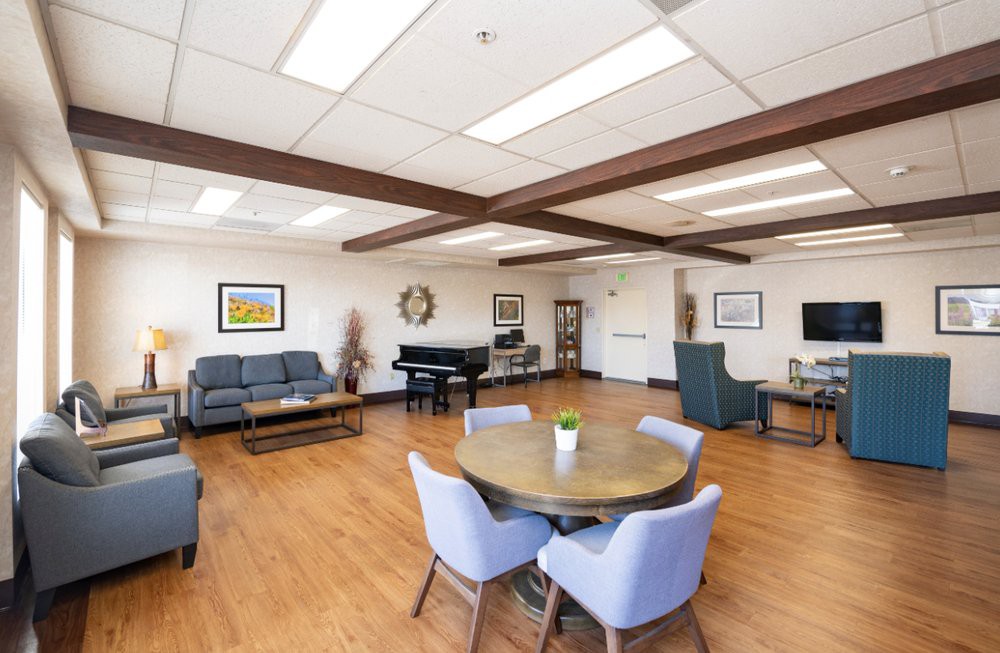 A spacious and bright lounge area featuring comfortable seating, a piano, and modern decor.