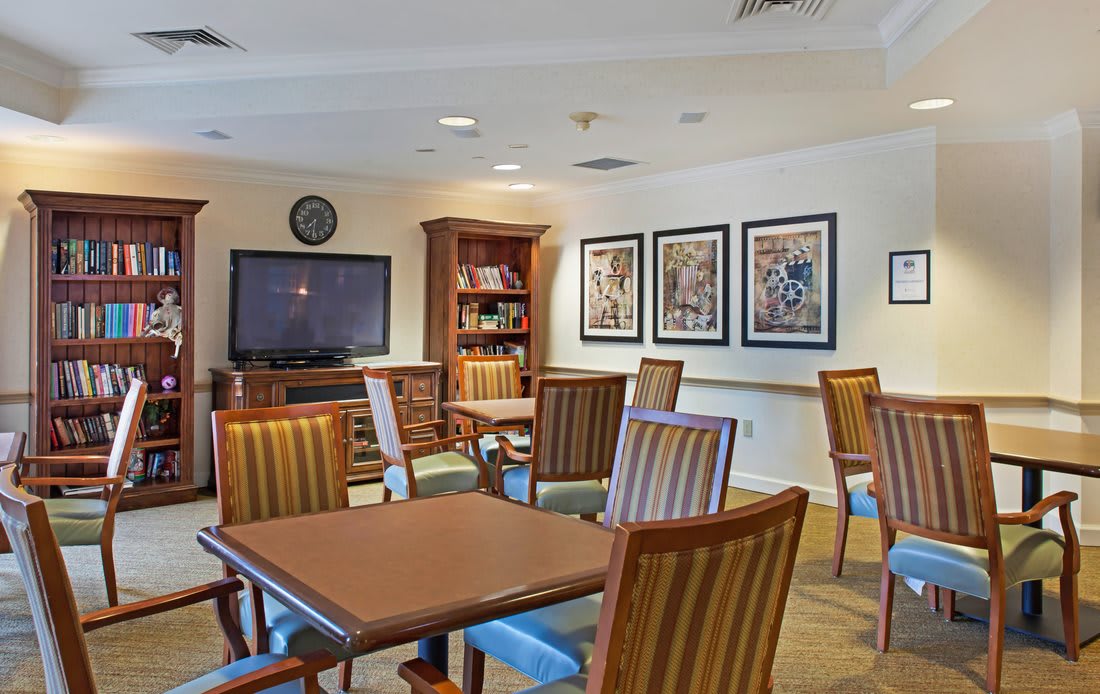 A cozy living room with wooden furniture, a large television, and framed artwork on the wall.