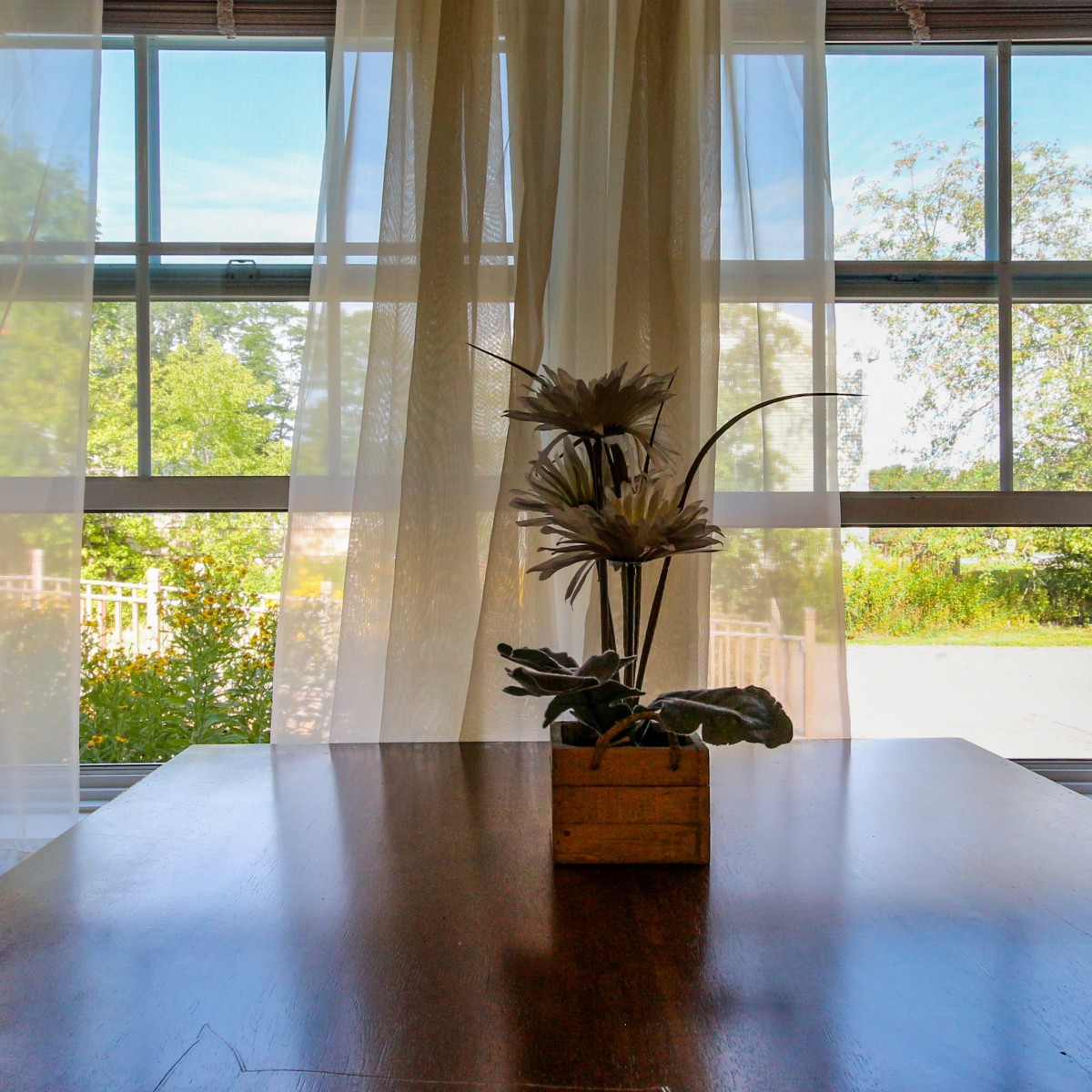 A serene interior scene with a flower arrangement on a table by a window.