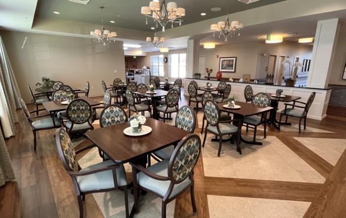 A well-arranged dining area with elegant tables and chairs, highlighted by chandeliers.
