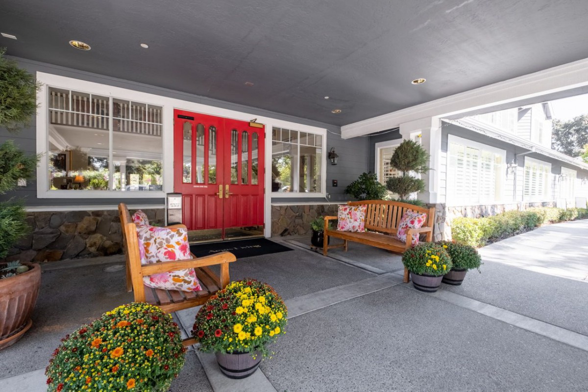 A welcoming front porch with a vibrant red door, cozy seating, and colorful potted plants.