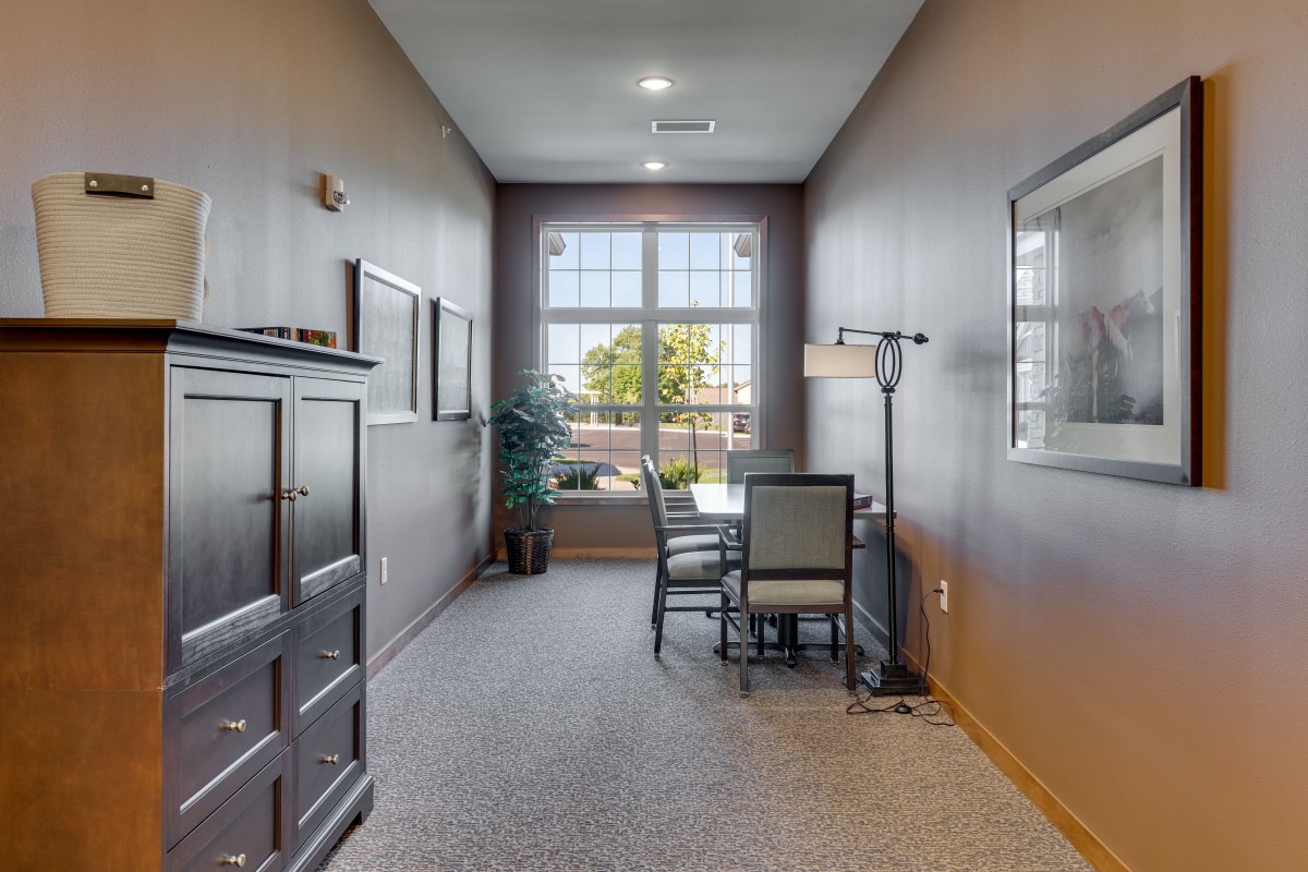 A modern office space with a large window, desk, and chairs.