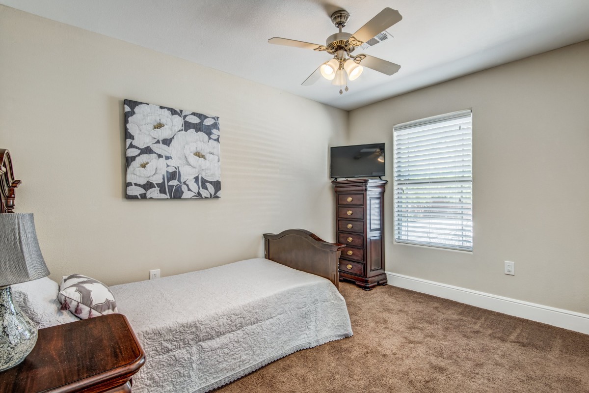 A cozy bedroom with a single bed, ceiling fan, and natural light from the window.