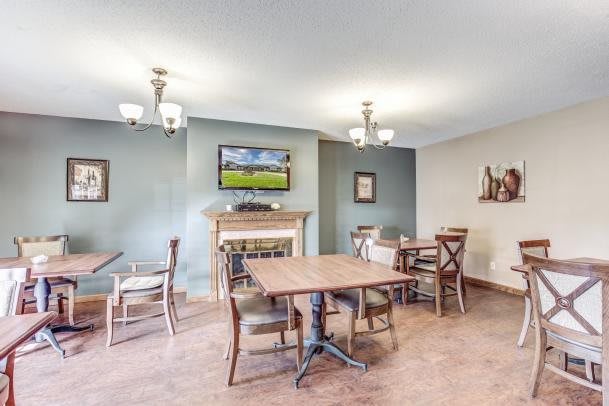 A cozy dining area with wooden tables and chairs, a fireplace, and a television mounted on the wall.