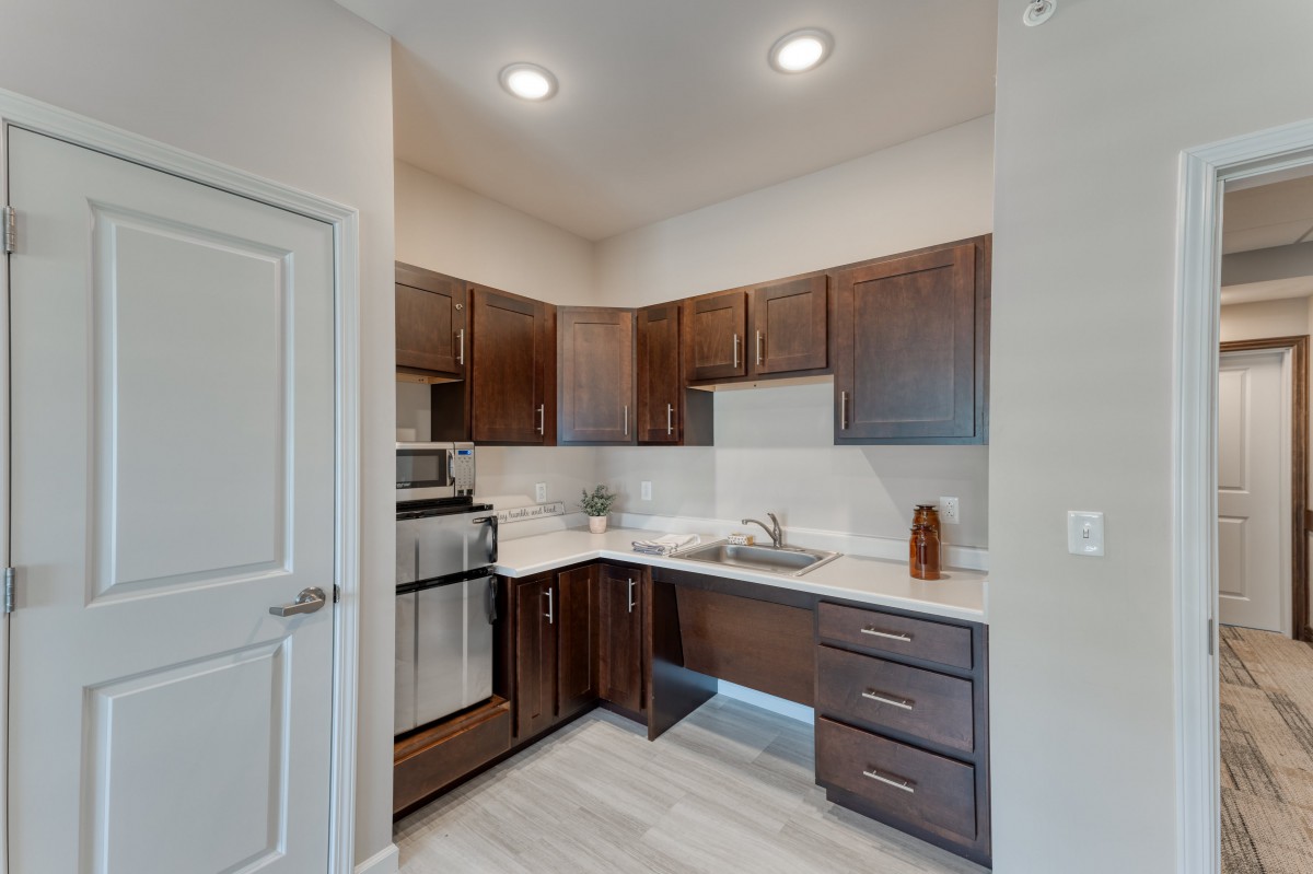 A modern apartment kitchen with dark wood cabinets and stainless steel appliances.