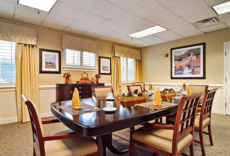 A well-decorated dining room with a large table and chairs, adorned with table settings and surrounded by artwork on the walls.
