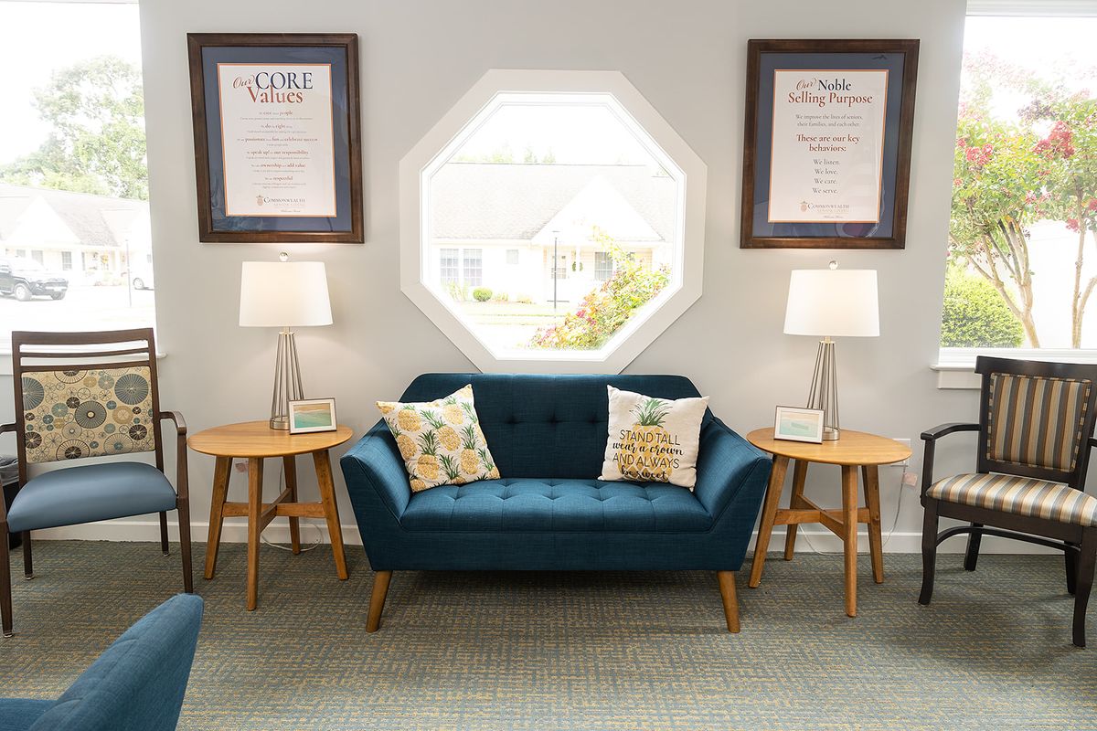 A cozy living room with a blue sofa, side tables, and an octagonal window.