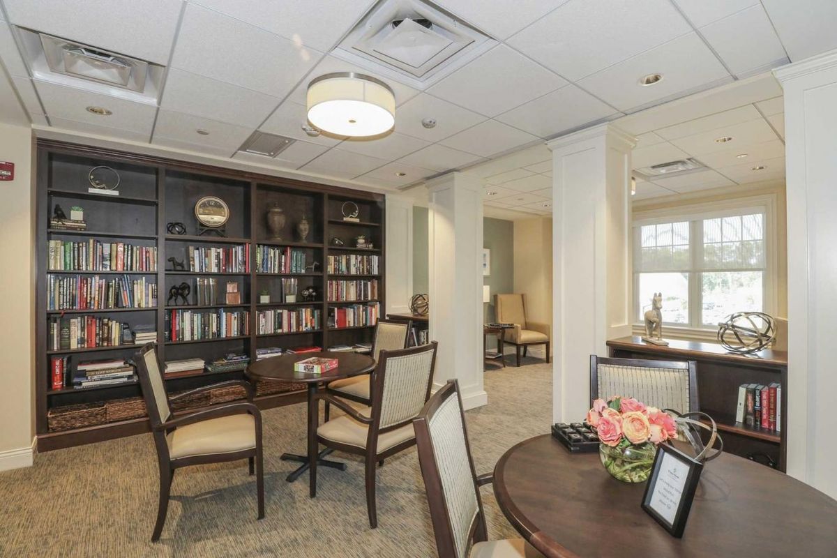 A cozy library room with bookshelves, tables, and chairs for reading.