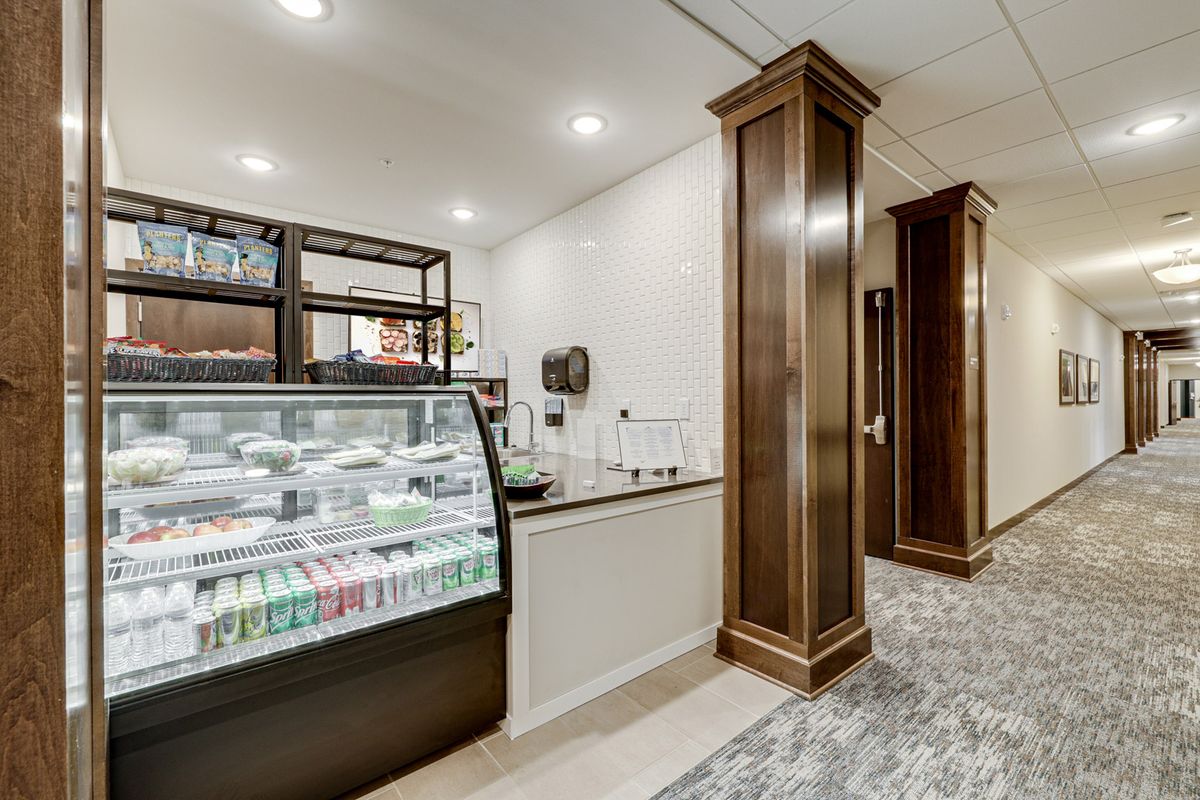 A cozy cafe interior featuring a refrigerated display case and wooden pillars.
