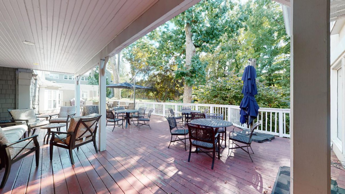 A spacious outdoor deck with seating and a view of lush trees.