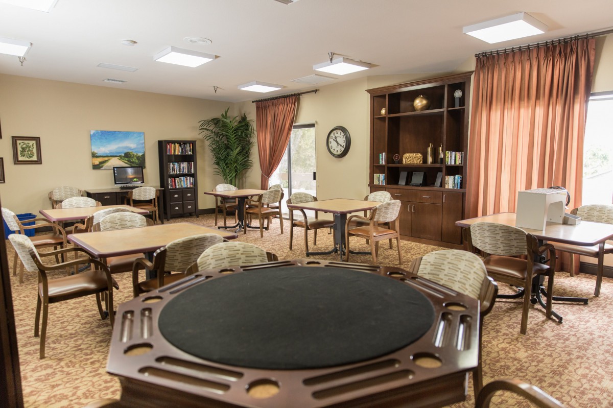 A cozy game room featuring a poker table, comfortable seating, and a well-stocked bookshelf.