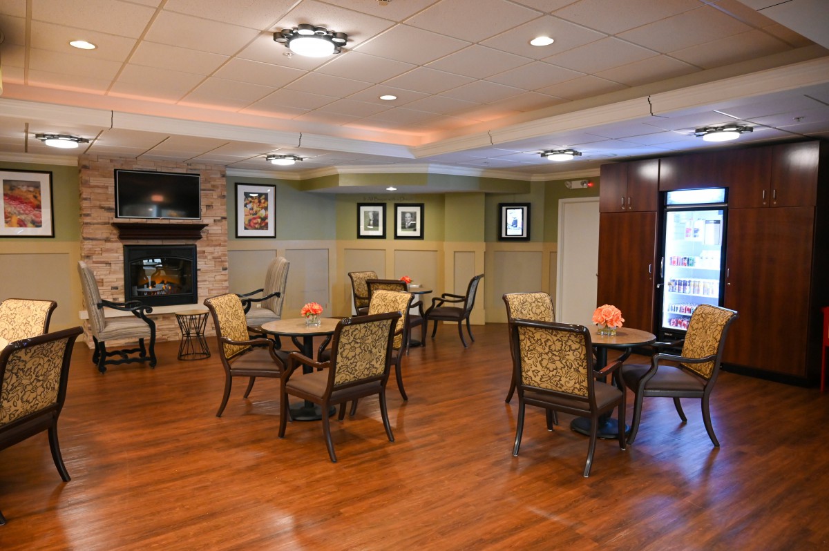 A cozy dining area with wooden floors, tables and chairs, a fireplace, and decorative lighting.