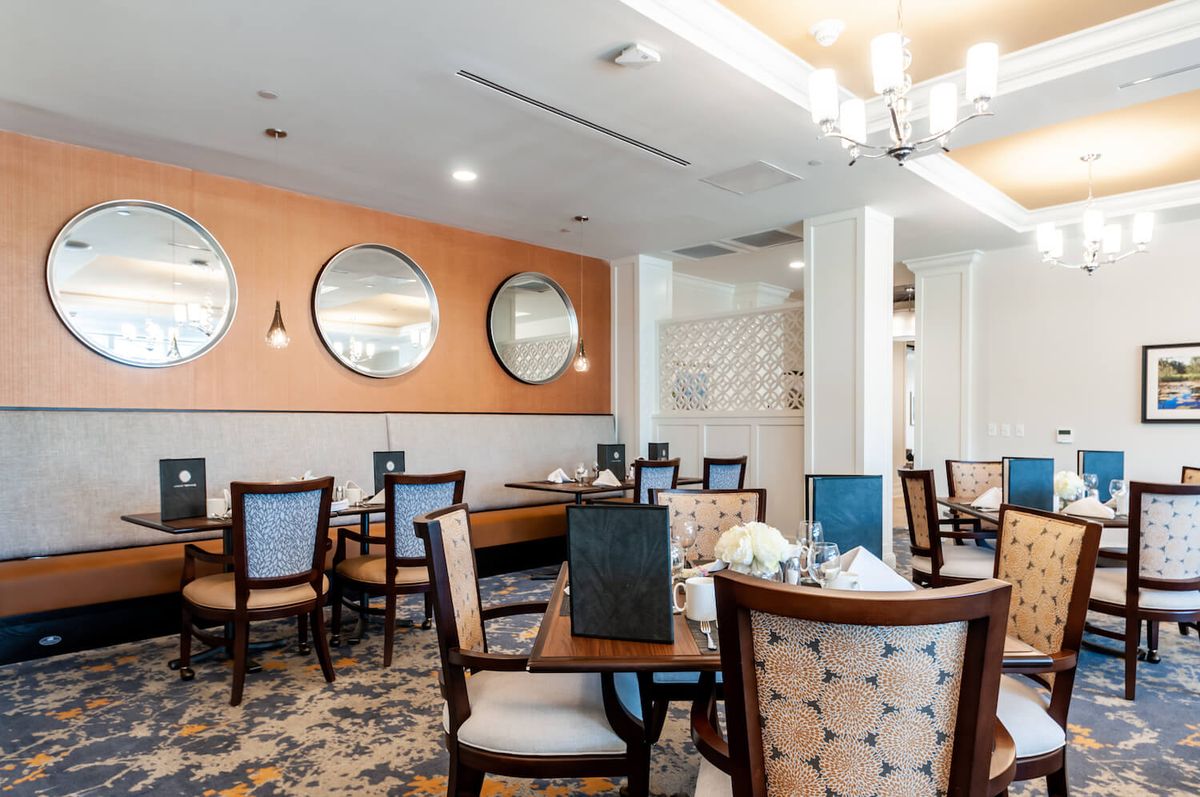 A neatly arranged dining room with stylish decor and round mirrors on the wall.
