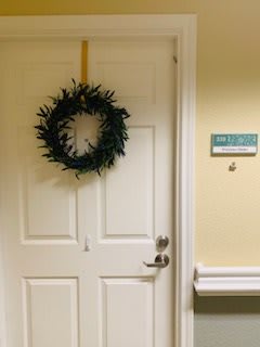 A decorated door with a wreath hanging in a hallway.
