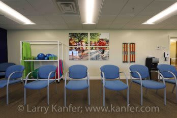A modern waiting room with blue chairs and colorful artwork on the walls.