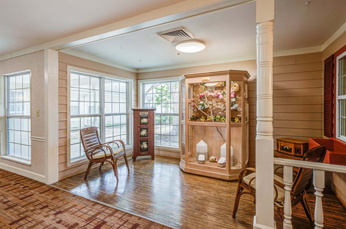A cozy living area featuring a display cabinet and ample natural light from large windows.