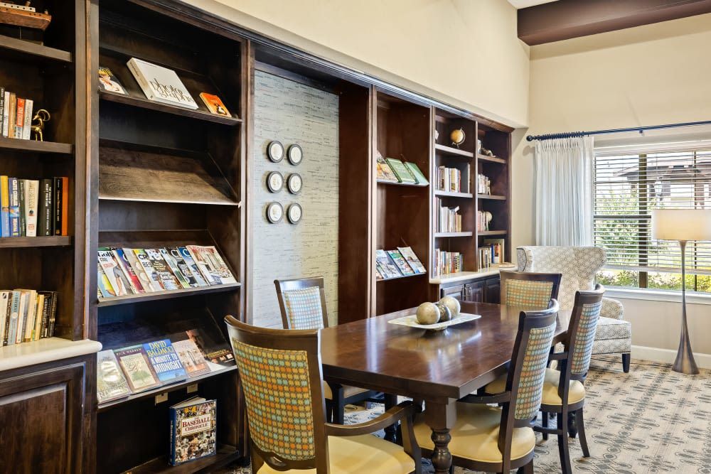 A cozy library with bookshelves, a table, and chairs for reading.