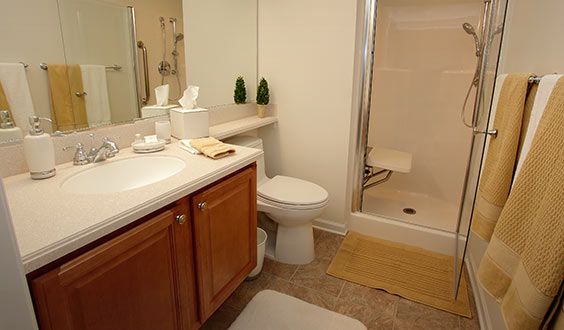 A tidy bathroom with a shower, toilet, sink, and mirror.