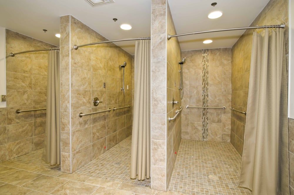 A modern, accessible shower area with tiled walls and curtains.
