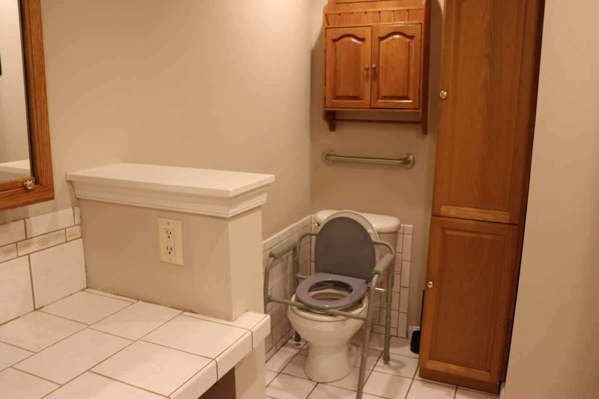 A bathroom featuring a toilet with safety rails and medical equipment for accessibility.