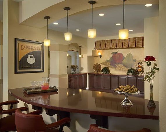 A modern kitchen with pendant lighting and a bar counter, featuring stylish artwork and seating.