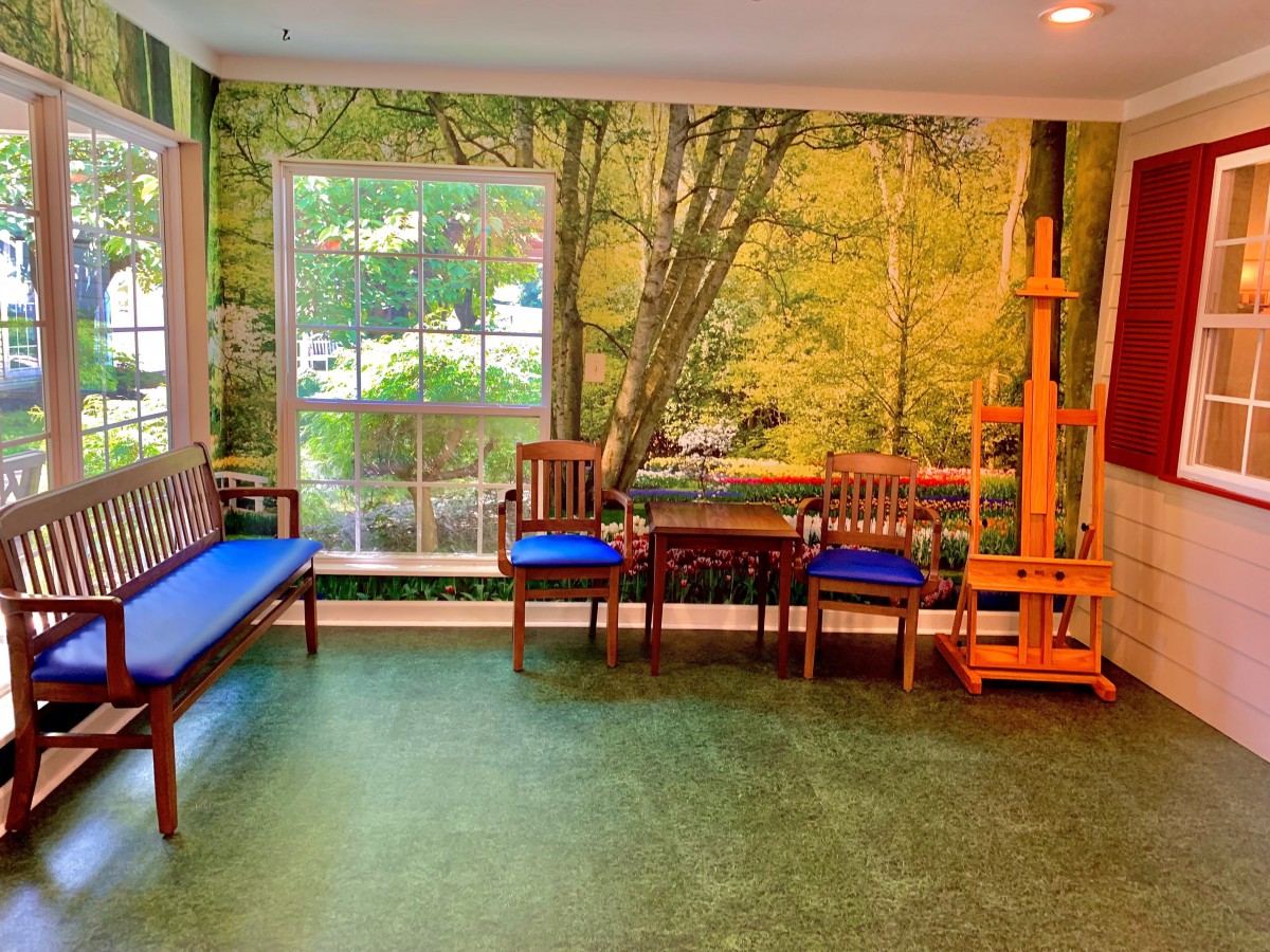 A cozy art studio with a forest mural, natural light, and seating.