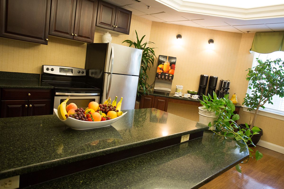 A modern kitchen with stainless steel appliances, a fruit bowl on the countertop, and a coffee station in the background.