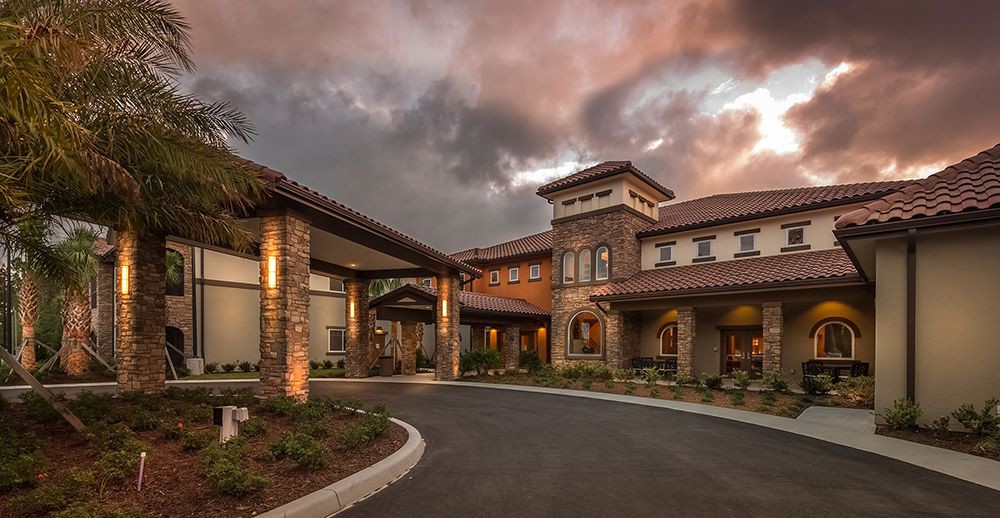 A beautifully designed building with a grand entrance and surrounding landscape under an evening sky.
