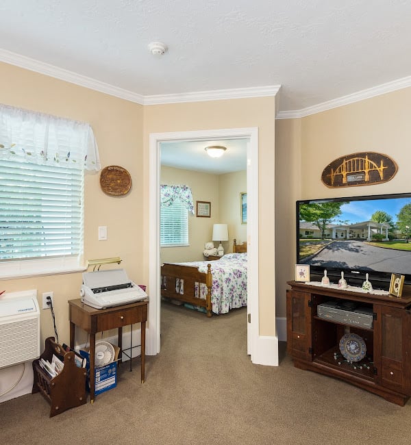 A cozy living room leading into a bedroom, featuring a television and elegant home decor.