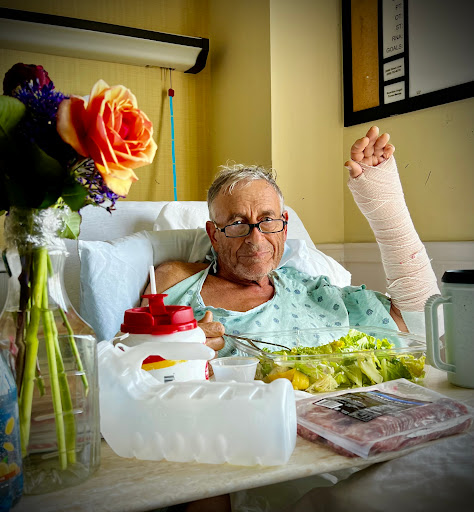 A patient in a hospital bed, enjoying a meal with flowers by their side.