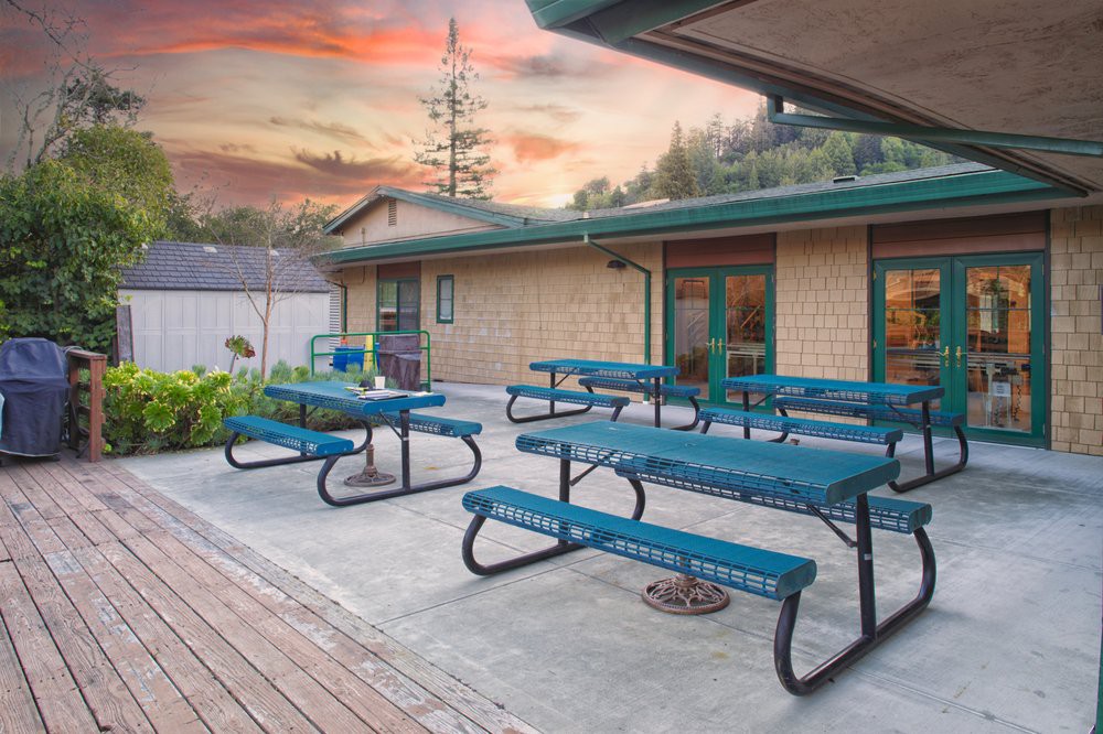 An outdoor patio with picnic tables under a vibrant sunset sky.