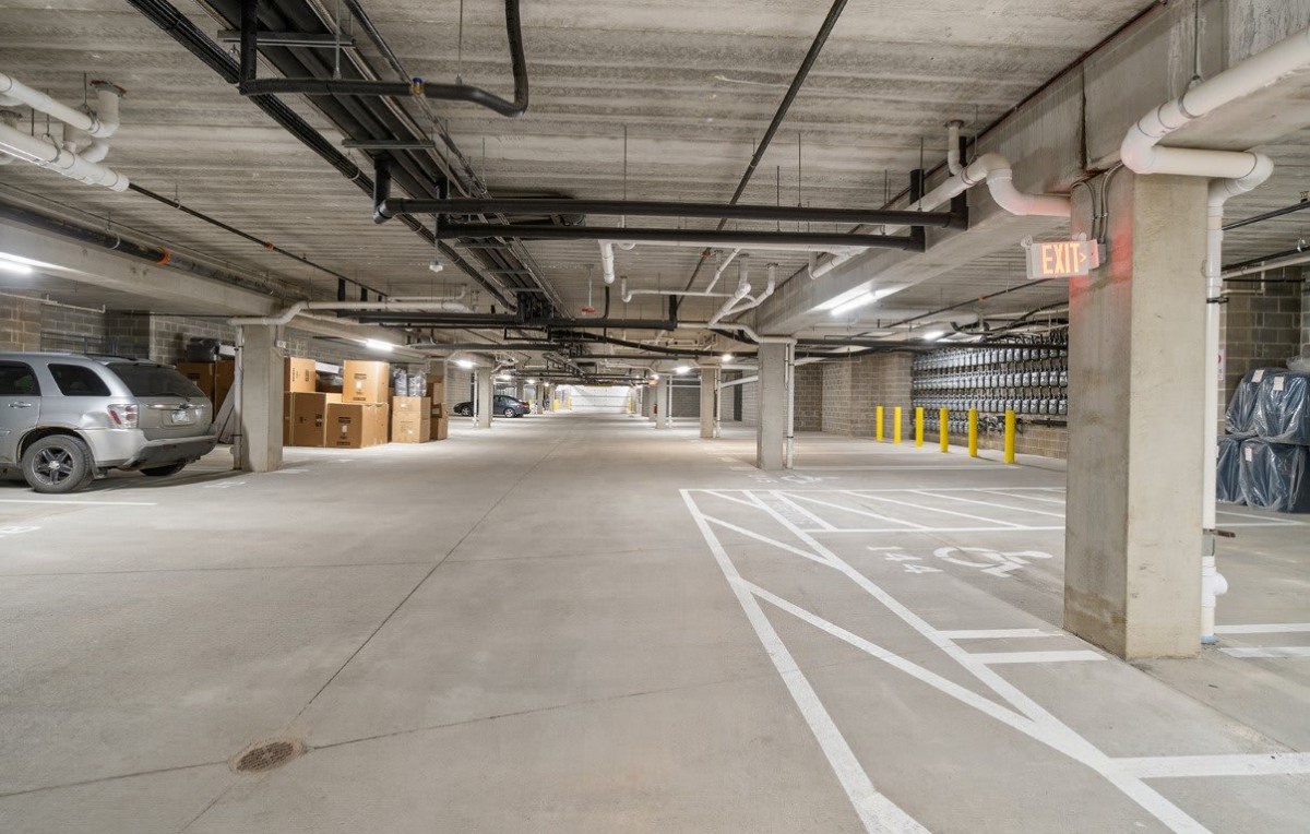 An empty underground parking garage with concrete floors and industrial lighting.