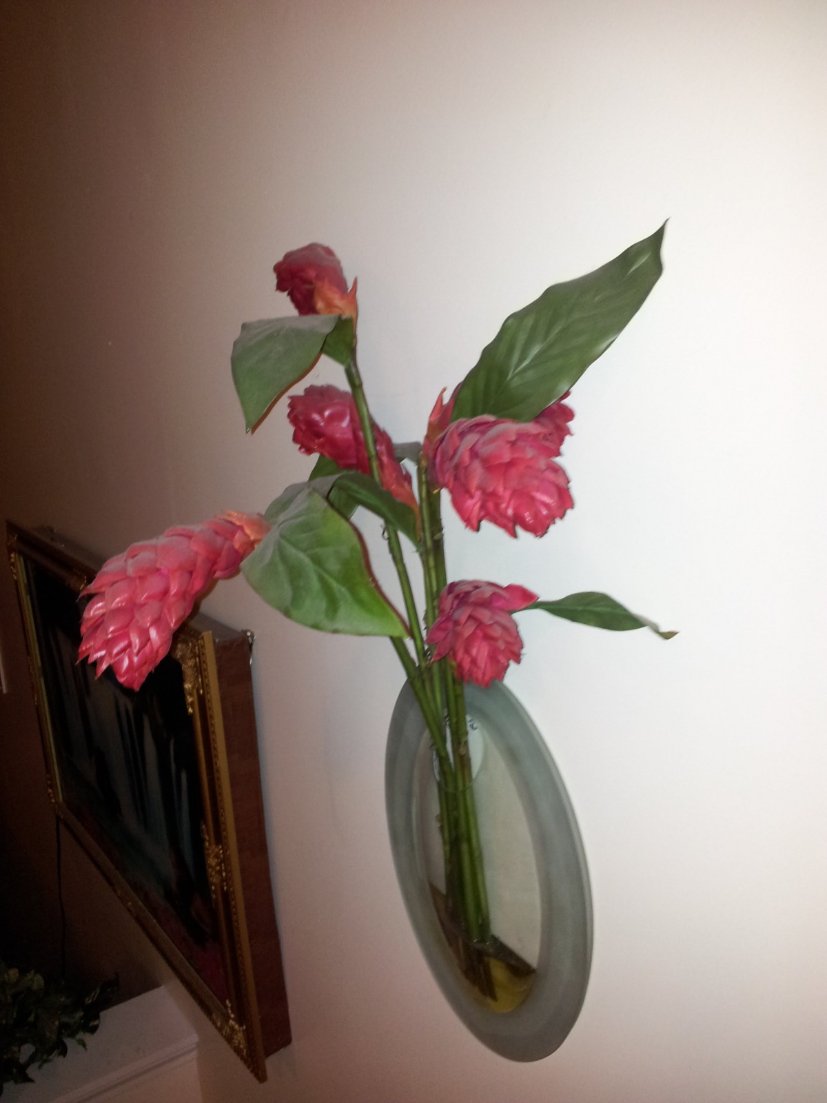 A vibrant ginger flower in a wall-mounted vase adds elegance to the indoor setting.