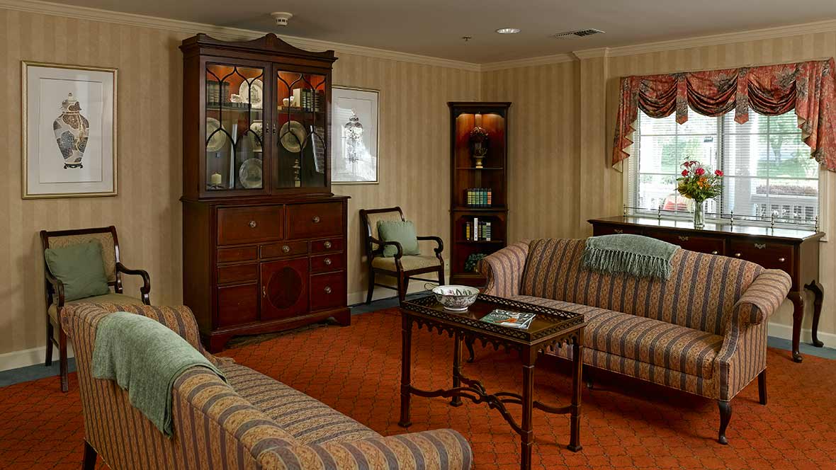 A traditional living room with striped sofas, a wooden cabinet, and a coffee table.