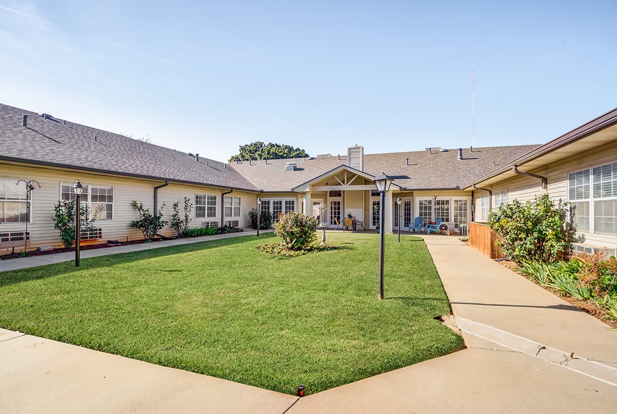 A well-maintained courtyard with a green lawn surrounded by a building.