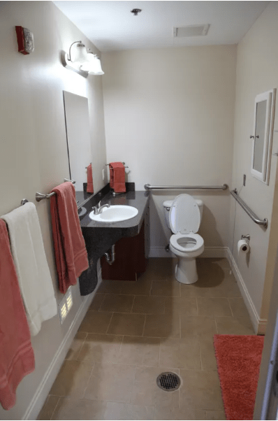 A clean bathroom with a sink, toilet, and coral-colored towels.
