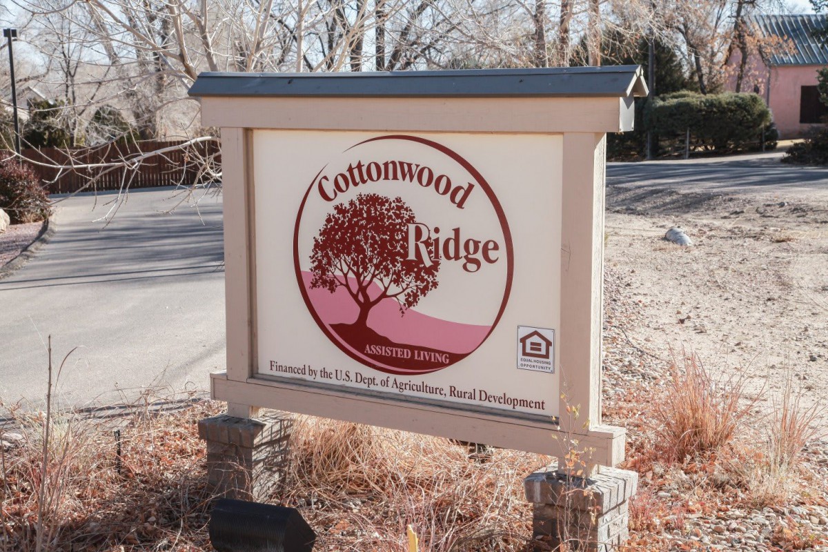 A sign for Cottonwood Ridge with a tree logo, located by the roadside.