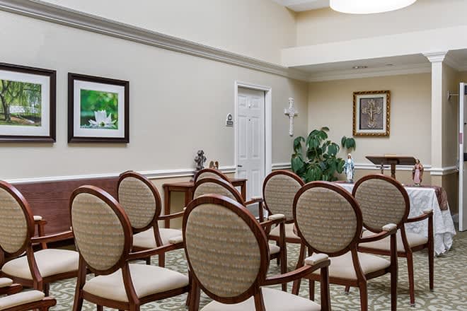 A small conference room with arranged chairs, artwork on the walls, and an indoor plant.