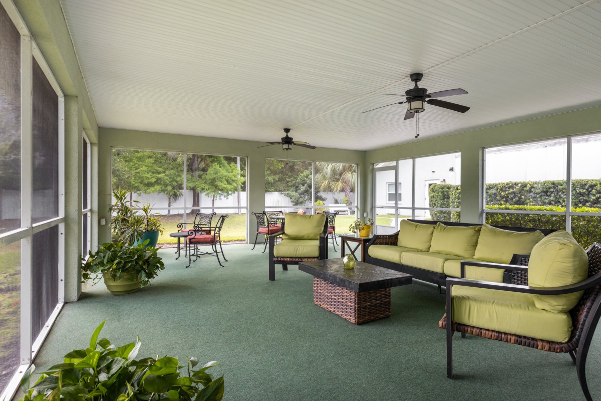 A spacious indoor patio with comfortable seating, green carpeting, and ceiling fans.