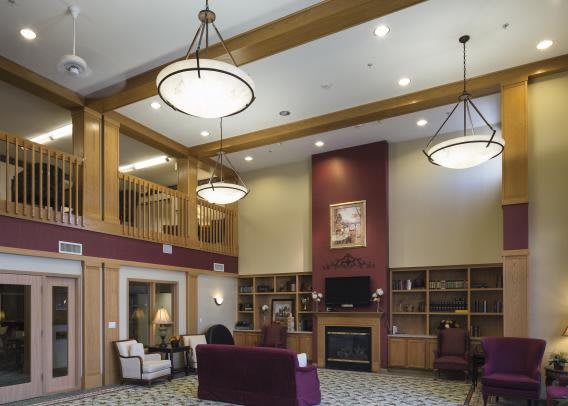 A cozy lobby area with comfortable furniture, warm lighting, and a fireplace surrounded by bookshelves.