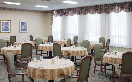 A spacious dining room set for guests, featuring neatly arranged tables and comfortable chairs.