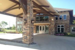 The entrance of a modern brick building with large windows and a covered walkway.