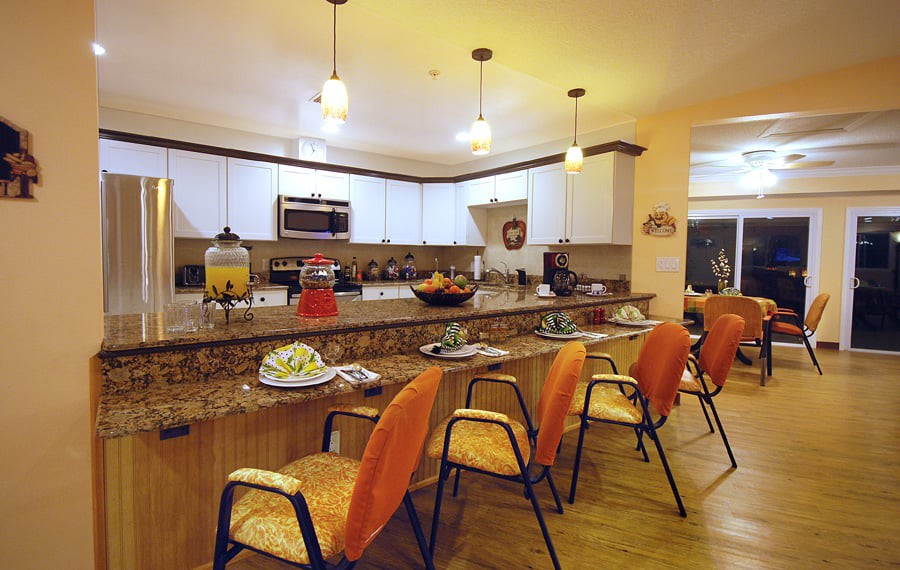 A modern kitchen interior featuring a granite countertop with bar stools and stylish pendant lighting.
