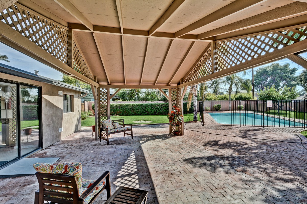 A spacious backyard patio with a pergola, outdoor seating, and a view of the swimming pool.